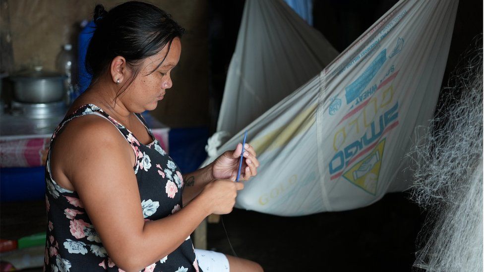 A woman works to repair a fishing net on the island of Palawan, Philippines